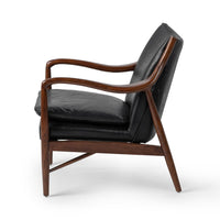 Side view of the Jet Black leather chair showing curved ash arms and tapered legs