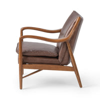 Side view of the Barrel Brown leather chair showing curved ash arms and tapered legs