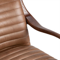 Close-up of channel-stitched tan leather back and seat beside a curved wood arm