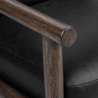 Rounded wood armrest detail beside the black leather seat