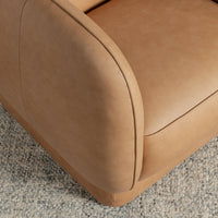 Tan leather swivel chair arm detail showing curved piping beside the seat