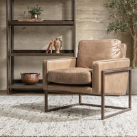 Tan leather accent chair with an iron frame styled beside wood shelving