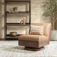 Tan leather swivel chair with a walnut shell styled with a patterned throw pillow beside shelving