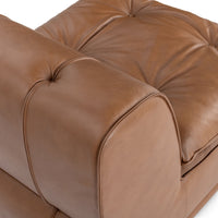 Close-up of the rounded leather back edge and button-tufted seat in toffee brown
