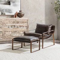 Truffle Brown leather sling chair styled with a separate footstool beside a carved cabinet