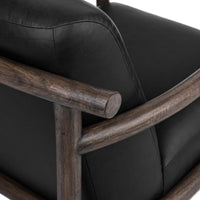 Black leather chair rear detail showing the stitched back and curved wood rail