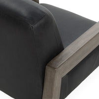 Black leather accent chair back detail with stitched edges and a wood arm
