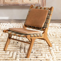 Tan leather armless accent chair with woven straps styled on a patterned rug