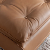 Close-up of a button and gathered folds on the toffee brown leather seat cushion