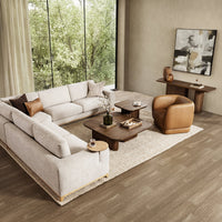Tan leather barrel-back chair styled in a living room with a sectional and wood coffee tables