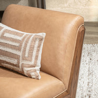 Tan leather swivel chair backrest detail, styled with a patterned throw pillow