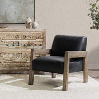 Black leather accent chair with an open wood frame styled beside a carved cabinet