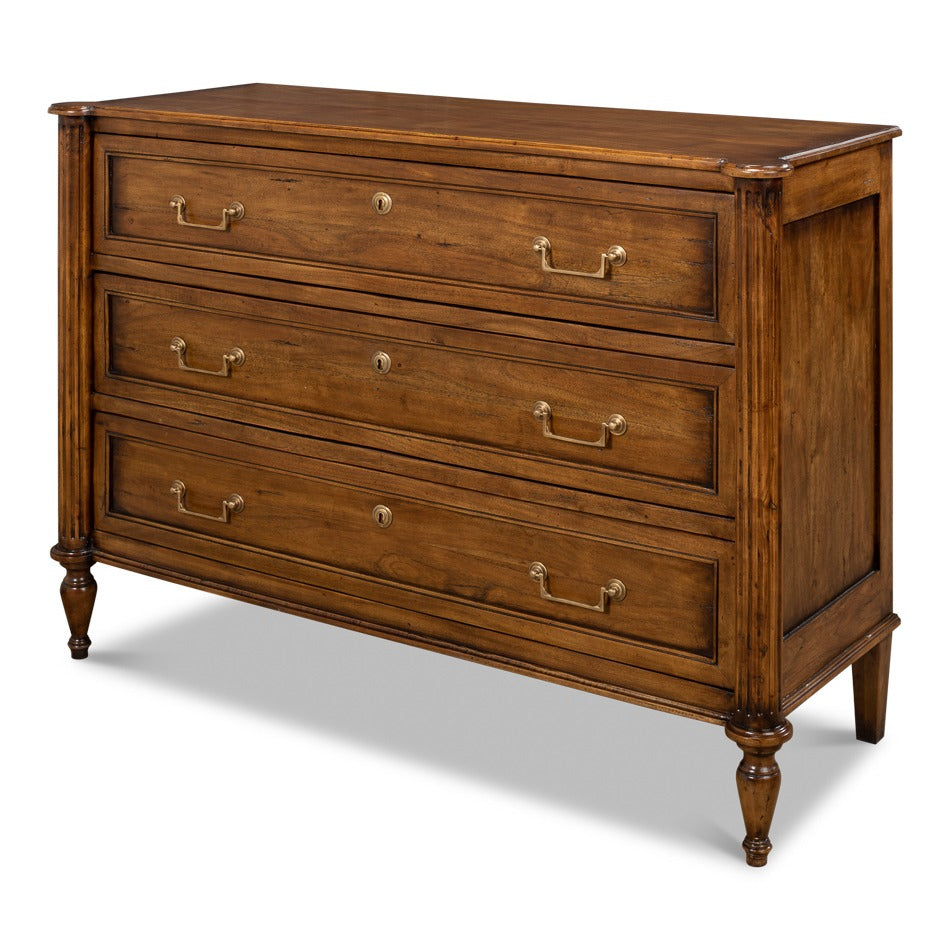 Traditional three-drawer walnut chest in fruitwood finish with brass bail pulls and faux keyhole escutcheons on turned legs