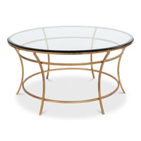Round coffee table with clear glass top and open iron base in antique gold finish