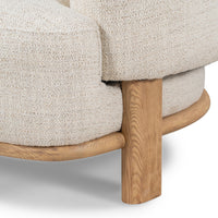 Ash leg and curved base rail beneath the Natural chair's textured upholstery