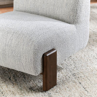 Close-up of the Ivory chair's textured seat beside a dark ash front leg