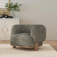 Green barrel-back accent chair styled on a woven rug beside a pale cabinet