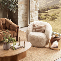 Sand swivel chair styled with a patterned pillow beside living-room tables