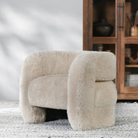 Sand faux fur accent chair styled on a rug beside a wooden cabinet
