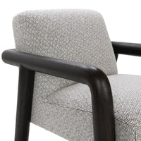 Close-up of the chair's pale textured upholstery and rounded dark wood arm