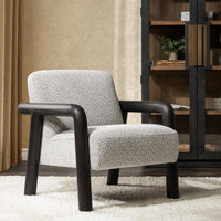 Dark wood-arm accent chair styled on a pale rug beside a cabinet