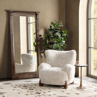 Vanilla wingback accent chair styled beside a floor mirror and small round table
