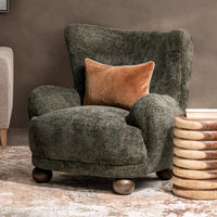 Winter Fir wingback chair styled with a rust-colored pillow beside a wood side table