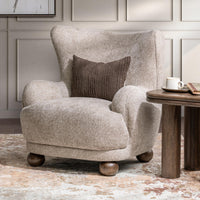 Mushroom Taupe wingback chair styled with a dark pillow beside a round side table