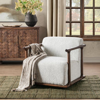 Ivory swivel chair styled with a draped throw on a green rug beside a window