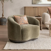 Olive Moss curved-back swivel chair styled with a patterned pillow on a woven rug