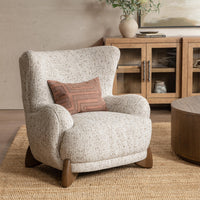 Canvas Oat wingback chair styled with a patterned pillow beside a wood cabinet
