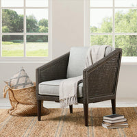 Gray rattan chair styled with a draped throw beside bright windows