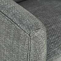 Close-up of the dark gray chair's arm corner and upholstery seams