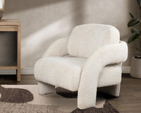 Natural curved-arm accent chair styled on a patterned rug beside a fireplace
