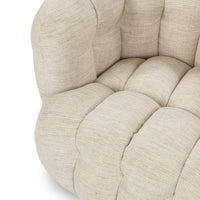 Close-up of the beige chair's deeply tufted seat and rounded front edge