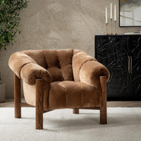 Bronze channel-tufted accent chair styled on a pale rug beside a dark cabinet