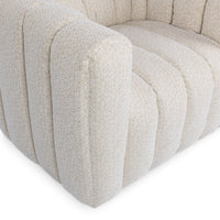 Close-up of the cream chair's channel-tufted arm and seat