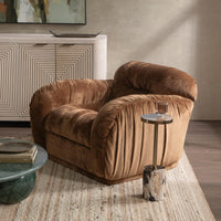 Bronze gathered accent chair styled on a rug beside a slender side table