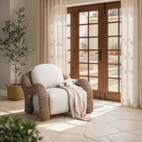 Natural rattan chair styled with a pale throw beside glazed wood doors