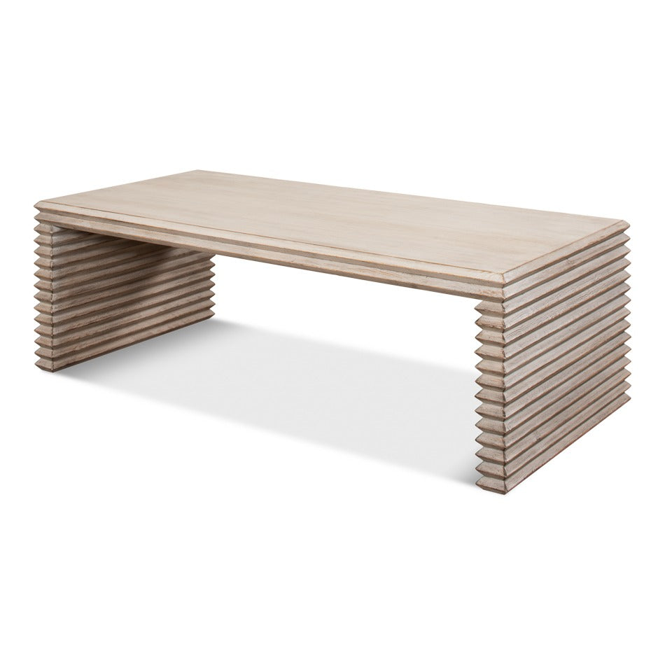 Long stacked-plank cocktail table in stone gray wire-brushed wood with ribbed end supports