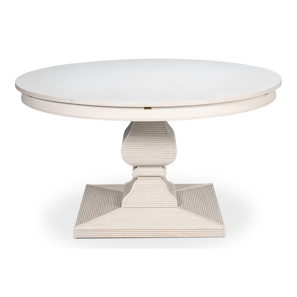 Round white reeded pedestal Jupe dining table with sculptural carved base and expanding top in a working white finish