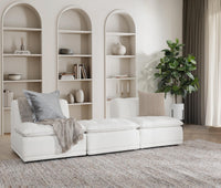 White upholstered seating arranged on a rug beneath arched shelves in a styled living room