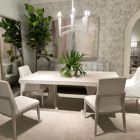 Elegant dining setting with white table and green plant.