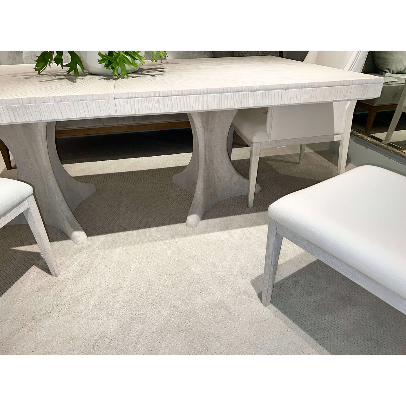 Close-up of dining table base and chairs, carpeted floor.