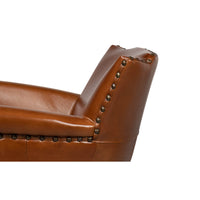 Close-up of leather armchair backrest with nailhead trim.
