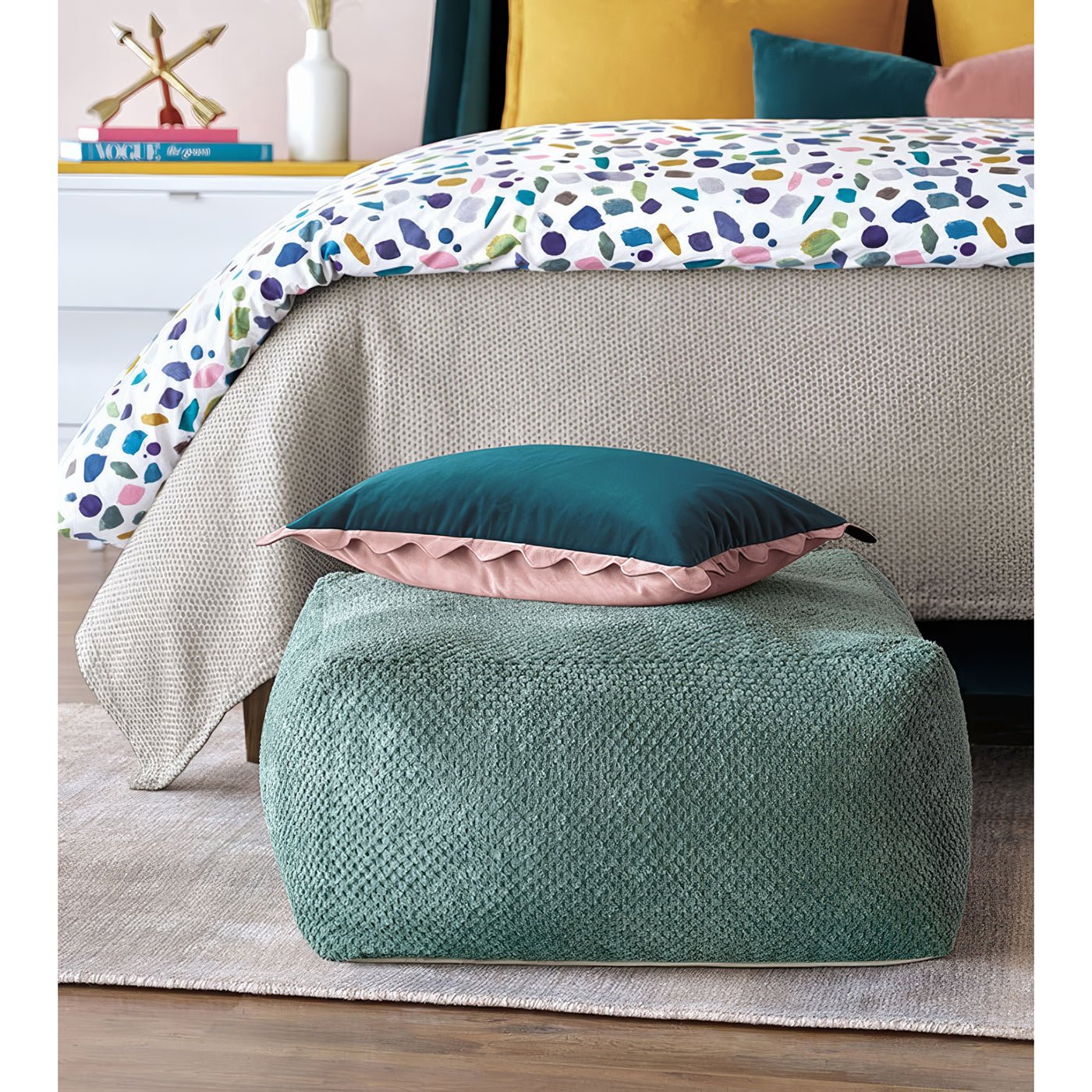 Aqua pouf with pillows, next to bed setup.