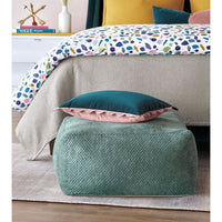 Aqua pouf with pillows, next to bed setup.