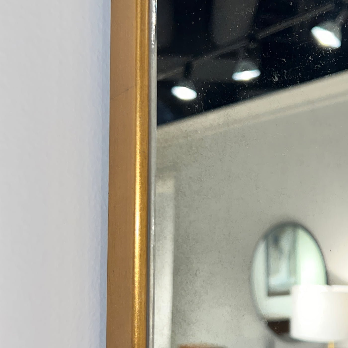 Close-up of arch mirror edge showing gold detail.