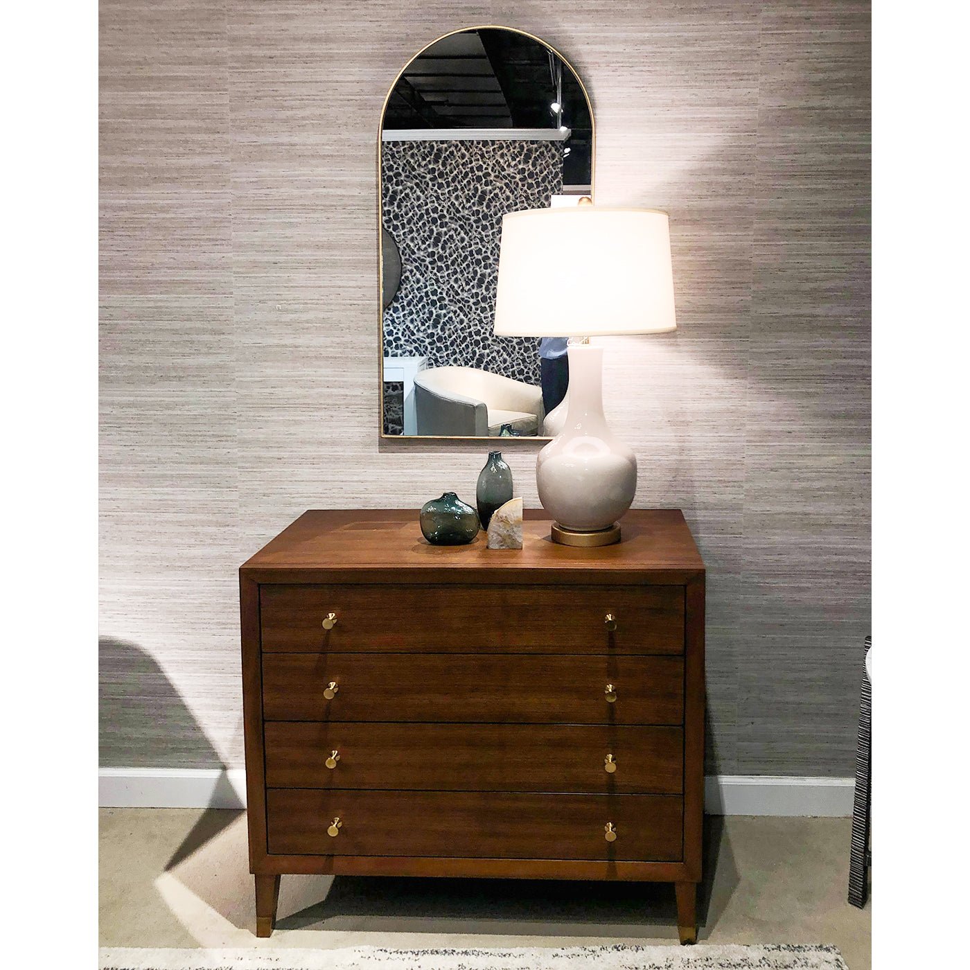 Arch mirror above dresser with lamp in room setup.