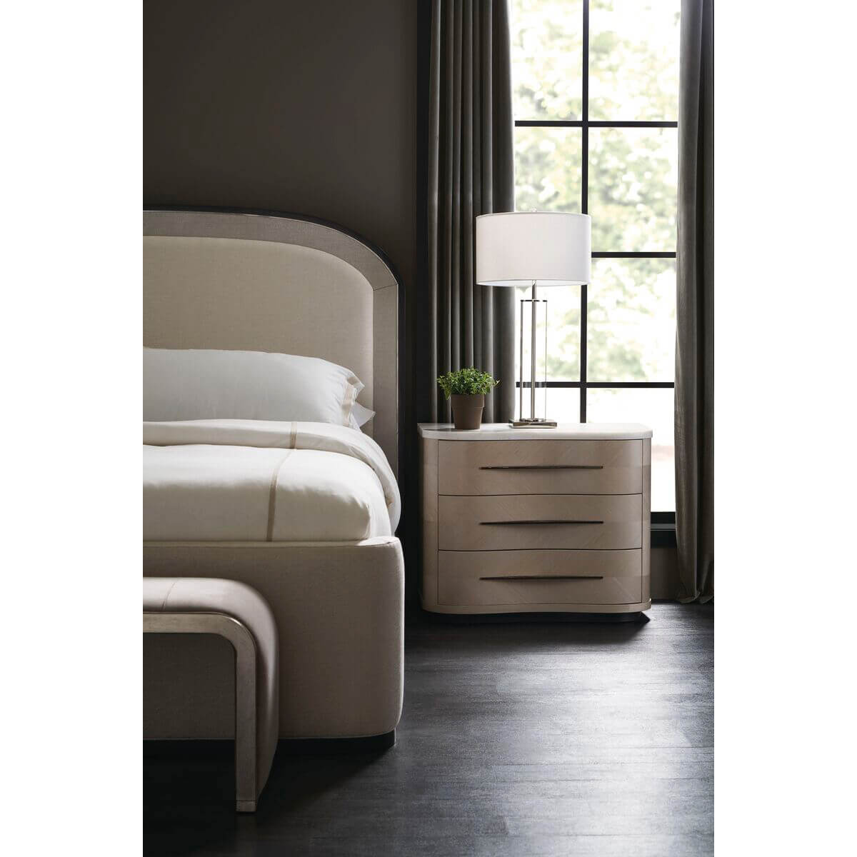 Arched Art Deco king bed with bedside table and lamp.